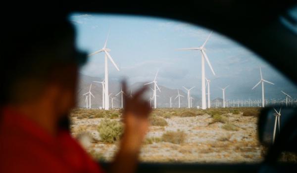 Man driving by a farm of wind turbines.