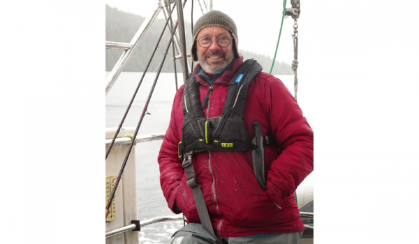 Dr. Ged McLean aboard the SV JACA, wearing a red coat and brown toque.