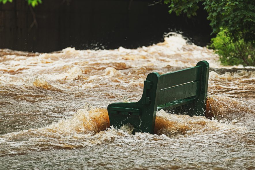 A park bench is surrounded by flood waters.